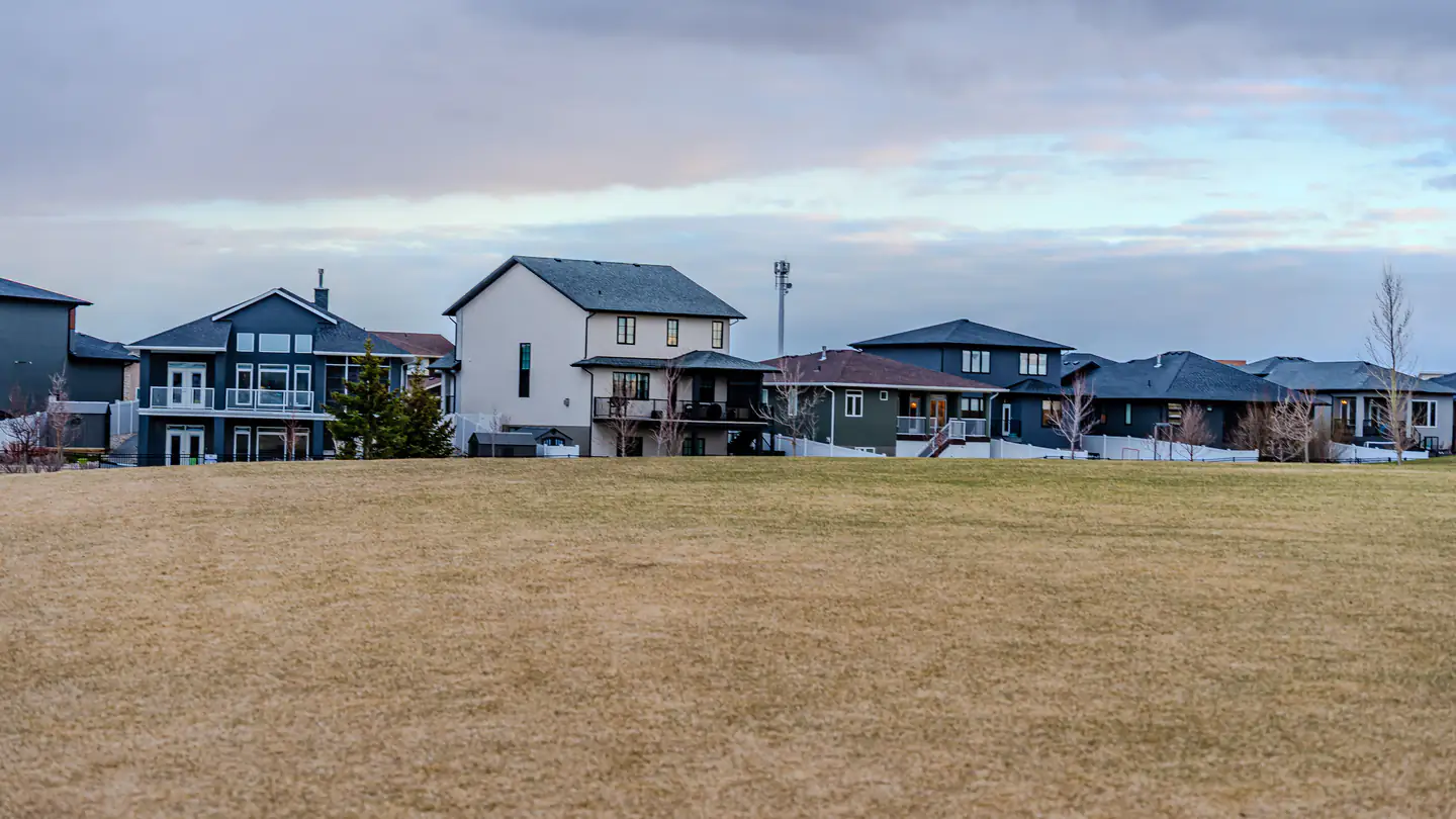 Newer two-story houses backing onto a wide open field at the edge of a subdivision.